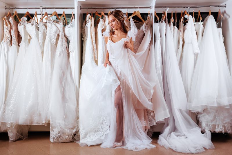 Mujer en tienda de vestidos de novia eligiendo vestido
